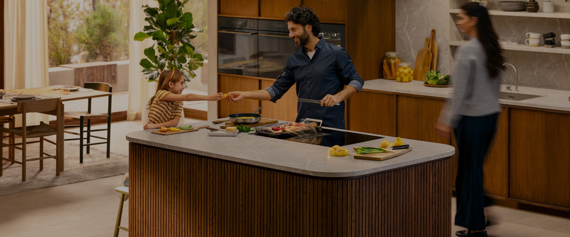 A family is cooking dinner together in a modern kitchen.