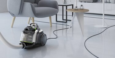 Një person që përdor kordonin ekstra të gjatë të Electrolux UltraFlex Green për të pastruar me lehtësi një dhomë ndenjeje